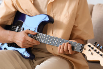person sitting with electric guitar in their lap