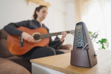 girl playing guitar with a metronome in focus