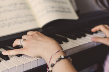 person playing piano with sheet music