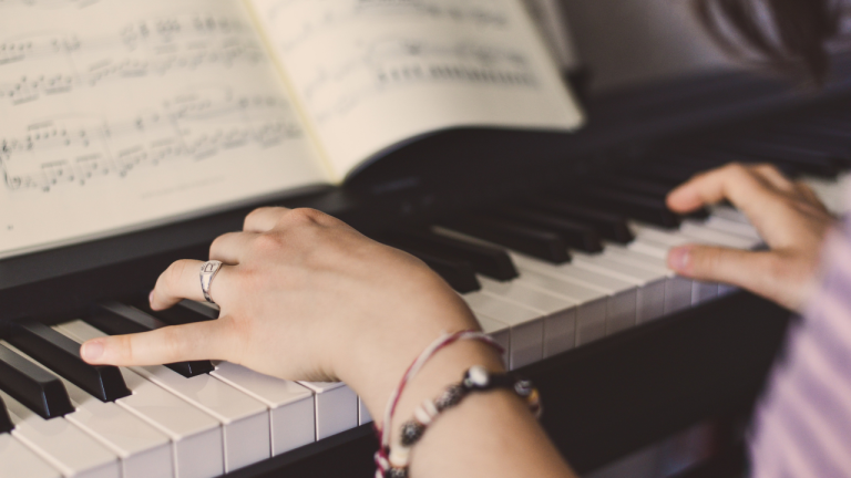person playing piano with sheet music