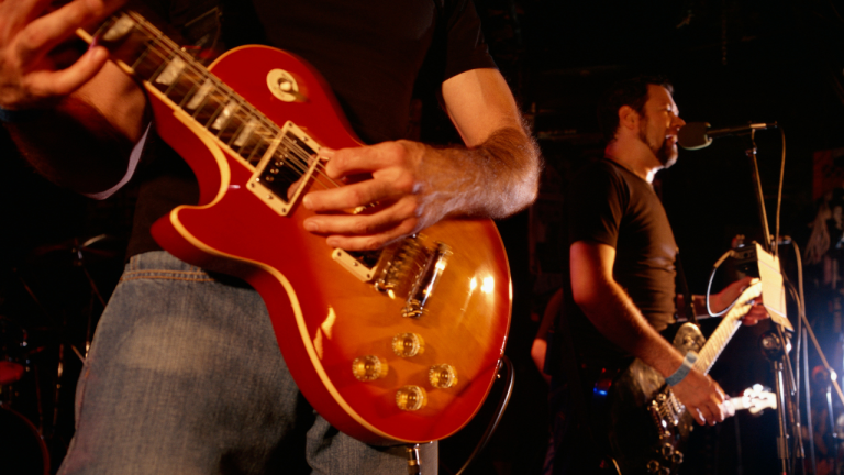 Close-up of a guitarist's red Les Paul guitar being played on stage.