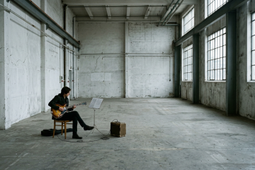Guitarist practices in a practice room with an amp and a music stand