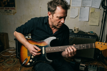 Guitarist in a private rehearsal room practicing the slap and mute technique