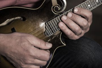 close up muted light photo of mike marshall's hands playing a Loar mandolin