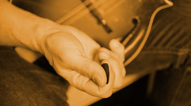 cepia tone closeup of a hand holding a blue chip mandolin pick