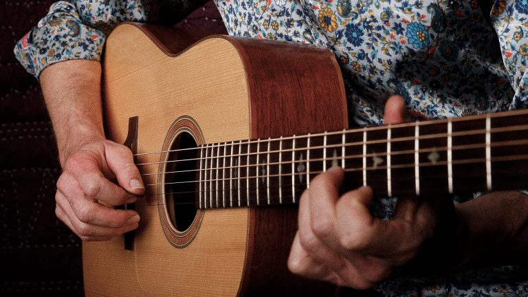Close-up of a flatpick striking the strings of an acoustic dreadnought guitar