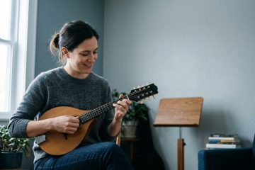 young women smiling playing mandolin in a practice room