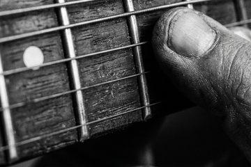 close up black and white photo of a finger pressed on a single string