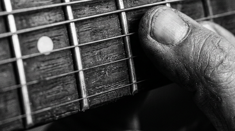close up black and white photo of a finger pressed on a single string