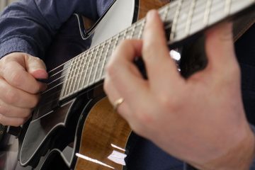 Close up color photo of Sean McGowan demonstrating the claw technique right hand shape playing multiple strings at the same time on guitar