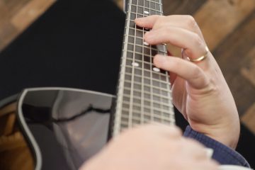 Close up color photo of Sean McGowan's fretting hand demonstrating a chord on a hollow body guitar