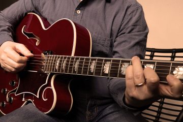 Close up of Sean McGowan playing a hollow body guitar demonstrating thumb muting technique