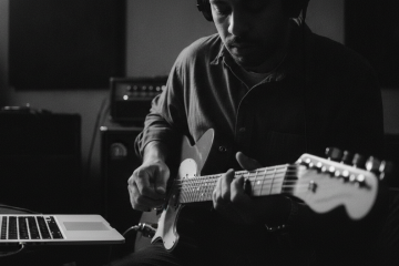 black and white photo of guitarist playing in front of a laptop practicing thirds and sixths