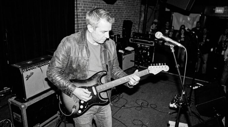 black and white photo of a middle aged man playing live over the V chord in a 12 bar blues jam