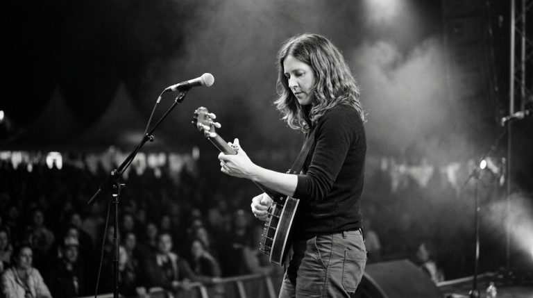black and white photo of a female banjo player playing banjo backup on stage at a night