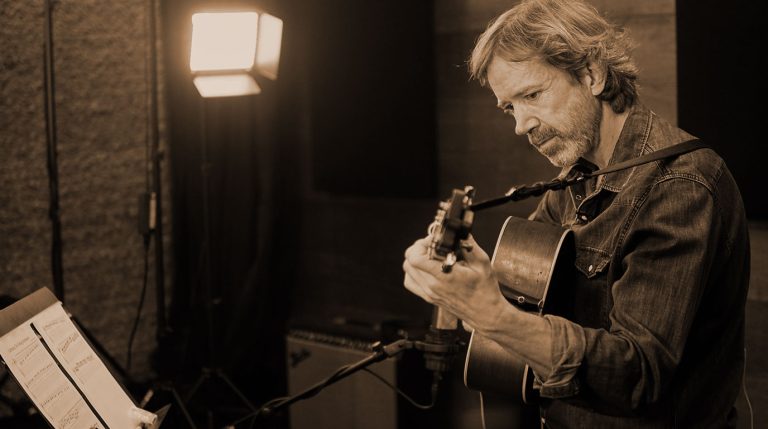 Tyler Grant teaches flatpicking in the studio, demonstrating how to learn a song