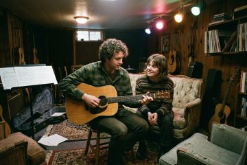 a young man plays guitar with a female friend, demonstrating relaxed guitar poster