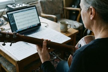woman guitar player practicing in a home office working on technique routine warm ups