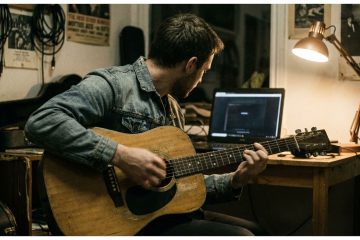 Young man practices how to accompany yourself on guitar using a melody strum approach