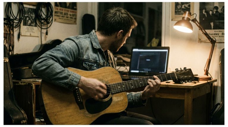 Young man practices how to accompany yourself on guitar using a melody strum approach