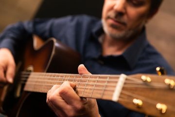 Dave Isaacs in the studio playing an acoustic guitar teaching how to practice a new song