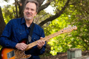 Dave Isaacs poses with his guitar as he prepares to teach you how to approach new songs on guitar