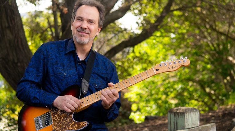 Dave Isaacs poses with his guitar as he prepares to teach you how to approach new songs on guitar