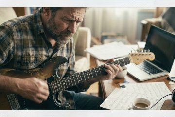 a man in his 50's practices how to use a chord chart on an electric guitar in a home practice room