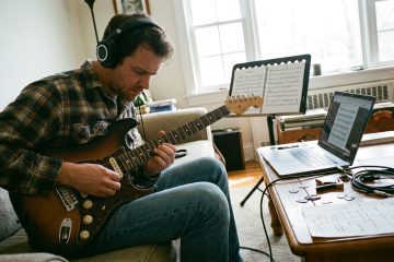 a young man practices guitar at home stuck on a hard part